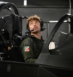 a man sitting in the cockpit of an airplane looking up into the sky with his headphones on