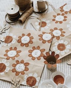 two brown and white paper bags sitting on top of a table next to twine spools