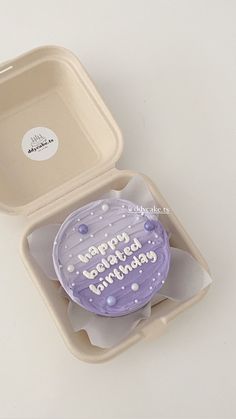 a birthday cupcake in a plastic container on a white surface with the words happy birthday written on it