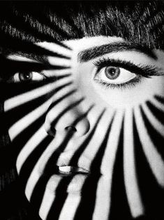 a woman's face is covered in black and white stripes with her eyes wide open