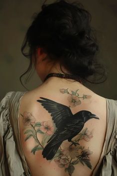 the back of a woman's shoulder with a black bird and flowers on it