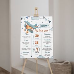 a wooden easel with a baby's first birthday calendar on it sitting in front of a white wall