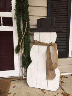 a snowman made out of wood sitting on the front porch