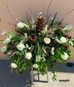 a flower arrangement with white flowers and pine cones