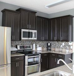 a kitchen with stainless steel appliances and dark wood cabinets, along with granite counter tops