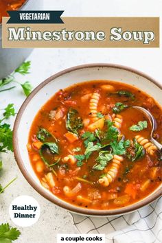 a bowl of minestone soup with pasta and parsley on the side next to a spoon