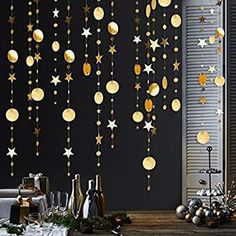 a table topped with christmas decorations and gold stars hanging from the ceiling next to a window