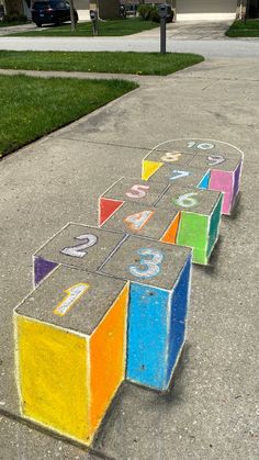 the sidewalk is made out of chalk and has numbers painted on it in different colors