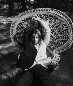 black and white photograph of a woman sitting on a bench in the grass with her arms behind her head