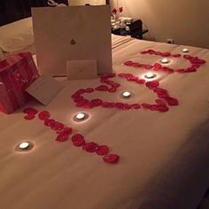 a bed topped with lots of candles next to a card that says i love you