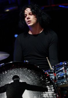 a man with black hair is playing drums