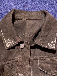 an old jacket with spider webs on the front and back buttons, sitting on a blue carpet