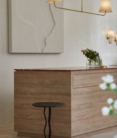 a wooden table sitting next to a white vase filled with flowers