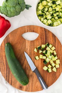 cucumbers, broccoli and peppers on a cutting board with a knife