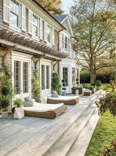 an outdoor patio with chaise lounges and potted plants on the side of it