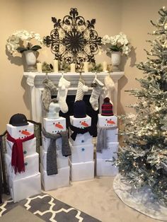 a christmas tree and presents in front of a fireplace decorated with snowmen, stockings and hats