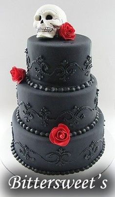 a three tiered cake with a skull and roses on the top is decorated in black frosting