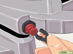 a hand holding a red object in front of a machine