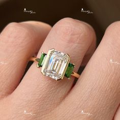 a woman's hand with an emerald and diamond ring