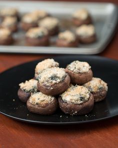 a black plate topped with mini mushrooms covered in cheese