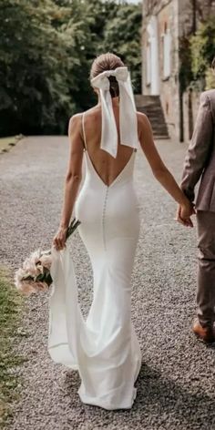 a bride and groom walking down the road holding hands