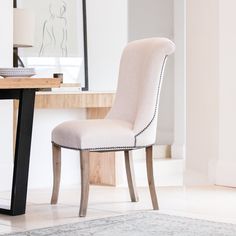 a white chair sitting in front of a mirror on top of a wooden table next to a rug