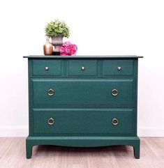 a green chest of drawers with flowers on top and a potted plant on top