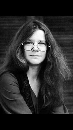 a black and white photo of a woman with long hair wearing glasses, looking at the camera