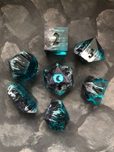 six blue and black dices sitting on top of a stone slab with numbers painted on them