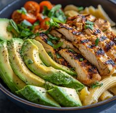 a bowl filled with pasta, chicken and avocado