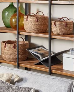 baskets and books on shelves in a living room with vases behind the bookcase