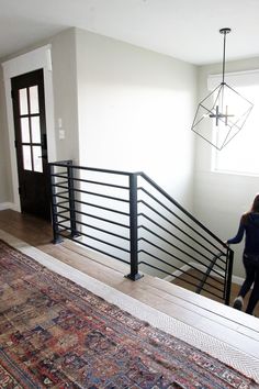 a woman is walking up the stairs in her house with an area rug on the floor