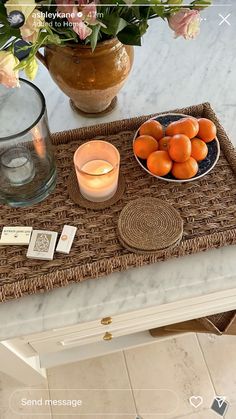 there is a bowl of oranges on the table next to a candle and some flowers