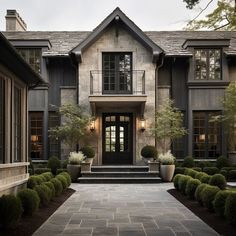 the front entrance of a large house with stone walkway and potted plants on either side