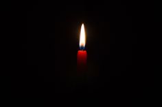 a single candle lit in the dark with only one light on it's side