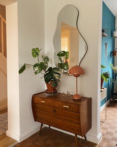 a mirror and some plants on a dresser in a room with blue walls, wood floors and wooden flooring