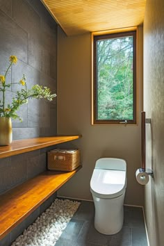 a white toilet sitting under a window next to a wooden shelf with flowers in it