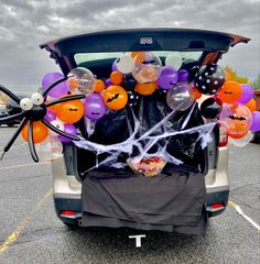 the trunk of a car decorated with halloween decorations and balloons in an empty parking lot