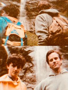 two men standing next to each other in front of a waterfall and wearing backpacks