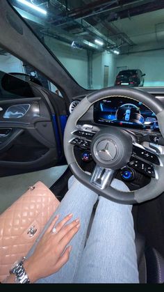 a woman sitting in the driver's seat of a car with her hand on the steering wheel