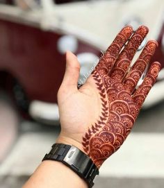 a woman's hand with henna tattoos on it and a car in the background