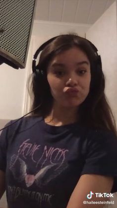 a girl wearing headphones and making a funny face in front of a recording microphone