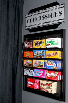 a vending machine that has some candy on it's display shelf next to a curtain