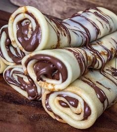 chocolate covered rolled up pastry sitting on top of a wooden cutting board