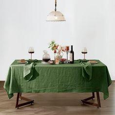 the table is covered with green linens and wine glasses