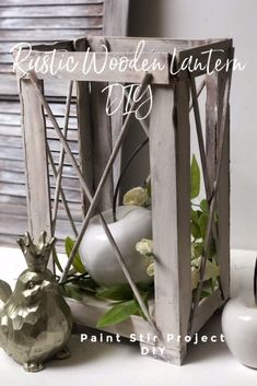 a white vase with flowers in it sitting next to a small metal bird and planter