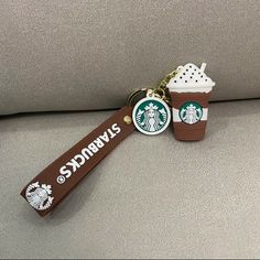 two starbucks key chains are sitting on a couch, one is brown and the other is white