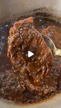 a ladle full of beef stew being spooned into the pot with meat in it