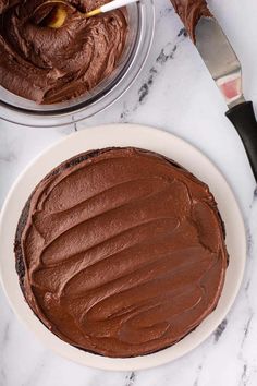 a chocolate cake sitting on top of a white plate next to a knife and fork