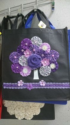 a black bag with purple and white flowers on it sitting next to other purses